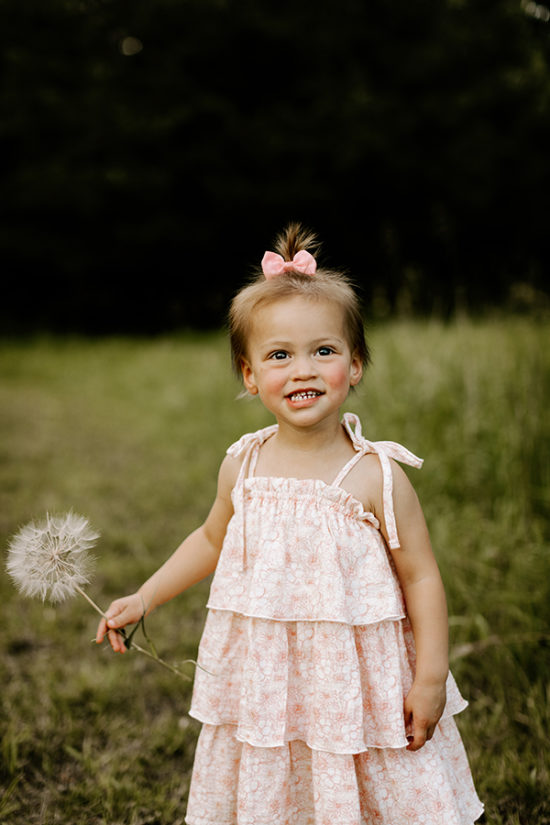 Toddler holds a flower while smiling at the camera