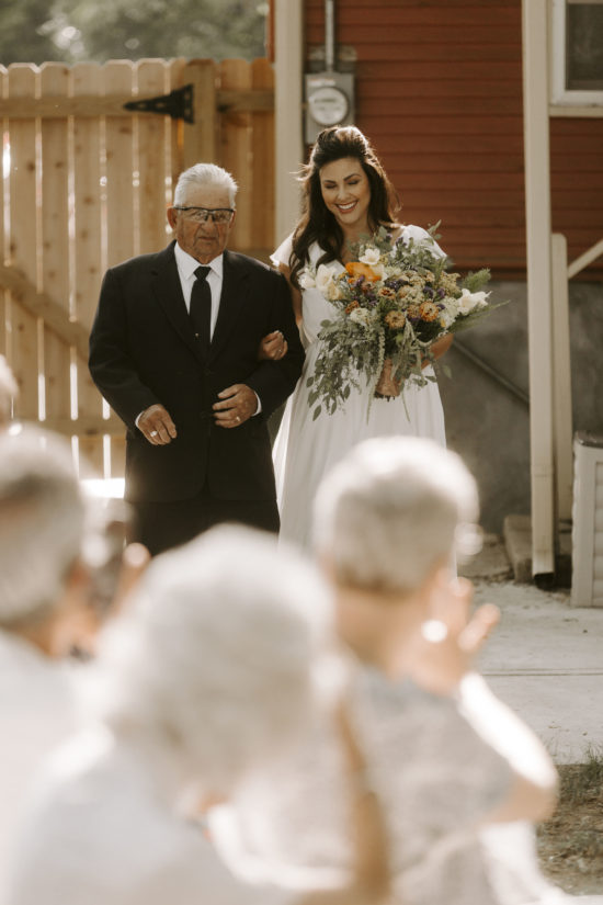A man in a suite walks his daughter down the aisle on her wedding day