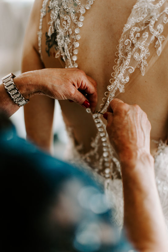 Mother buttoning bride's dress