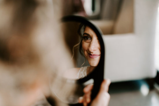 Bride looks in the mirror at her makeup