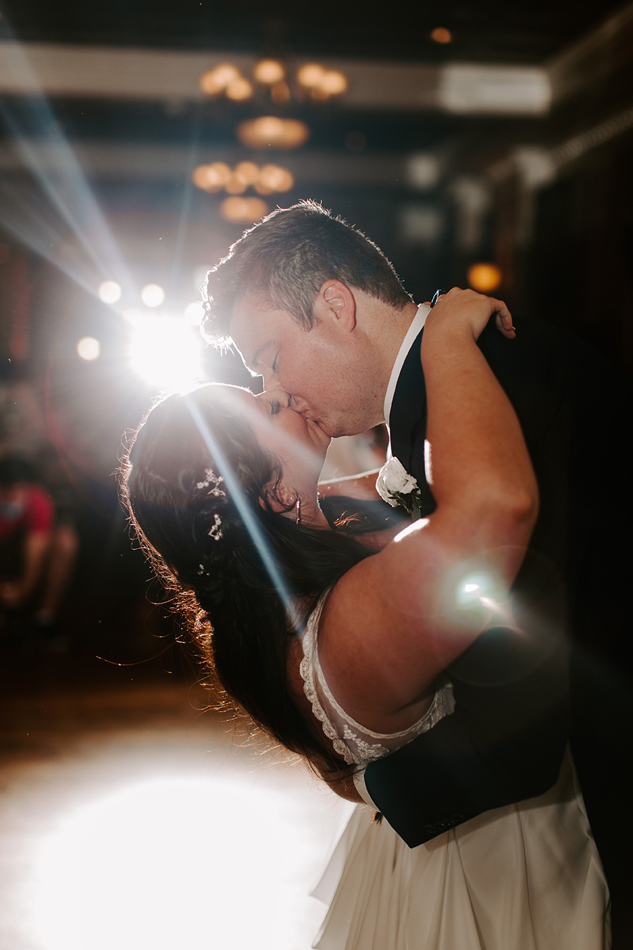 Groom dips his bride while leaning in for a kiss