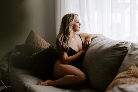 Woman on couch in lingerie, staring out of window, to show the power of boudoir