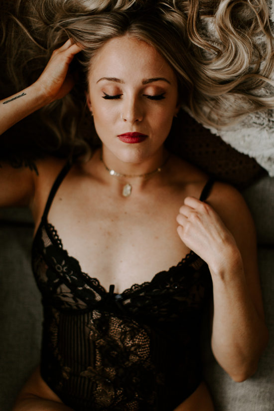 Woman posing on bed in lingerie with eyes closed to show the power of boudoir