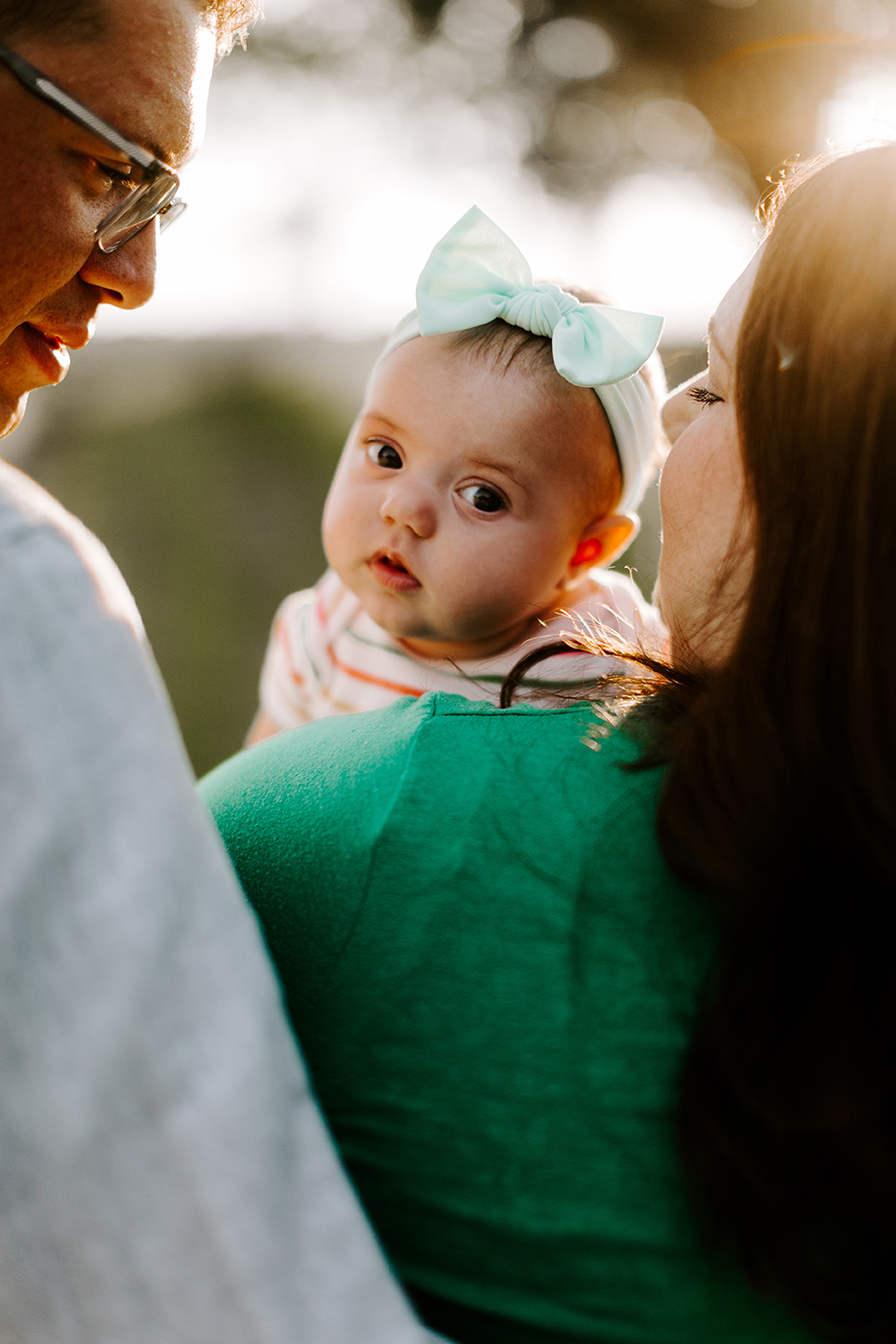 Baby peeks around her mom and dad for a family photo session