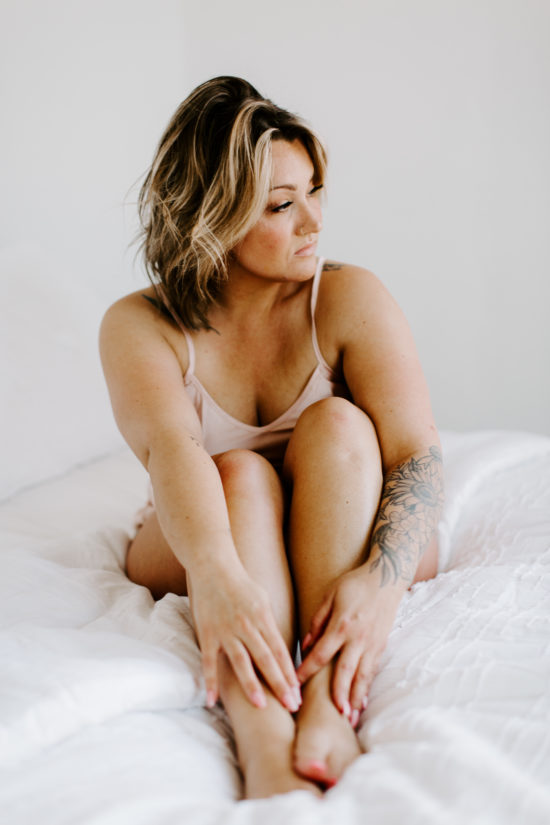 Boudoir sessions: Woman sits on bed posing