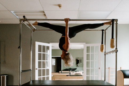 Woman hangs upside down from a pilates machine