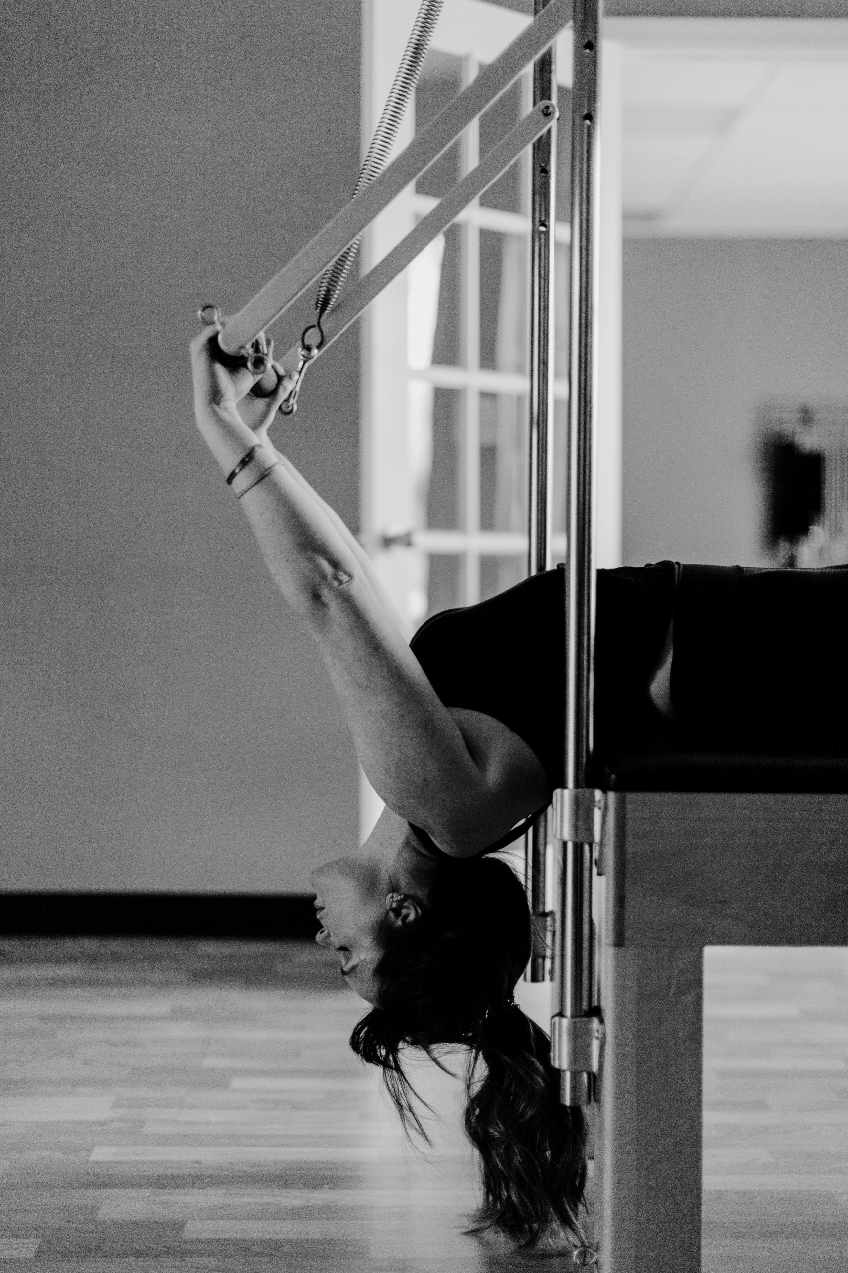 Woman hangs upside down using pilates equipment