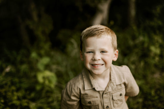 Boy grins at the camera during a family photo session