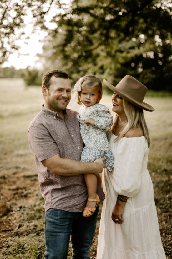 Couple poses with their daughter in a field during family photos