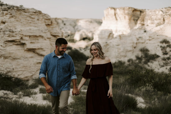 Couple smiles and holds hands while walking through the Little Jerusalem badlands