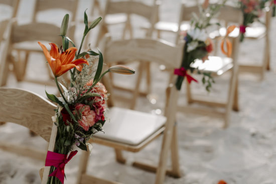 Wedding flowers in Mexico attached to chairs on the beach