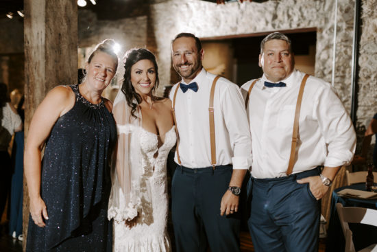 Newly married couple stands with friends at their wedding reception