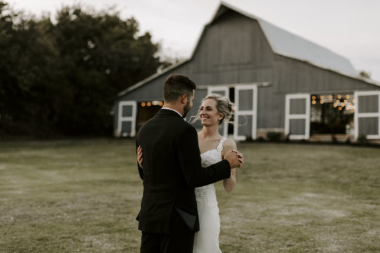 Bride and groom dance in front of their barn during their Kansas farm wedding
