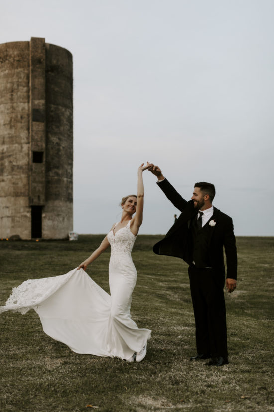 Bride and groom dance in front of a silo on their Kansas farm