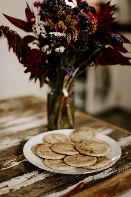 A plate of cookies sits on the table under bright fall flowers and color