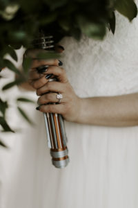 Bride holds her bouquet, which includes a custom-made Star Wars lightsaber flower holder