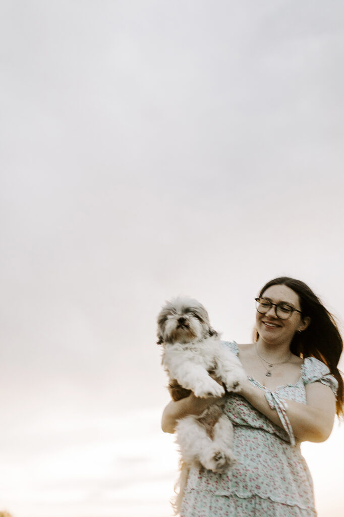 A woman holds her Shih Tzu while smiling during her Lawrence pet photo session.