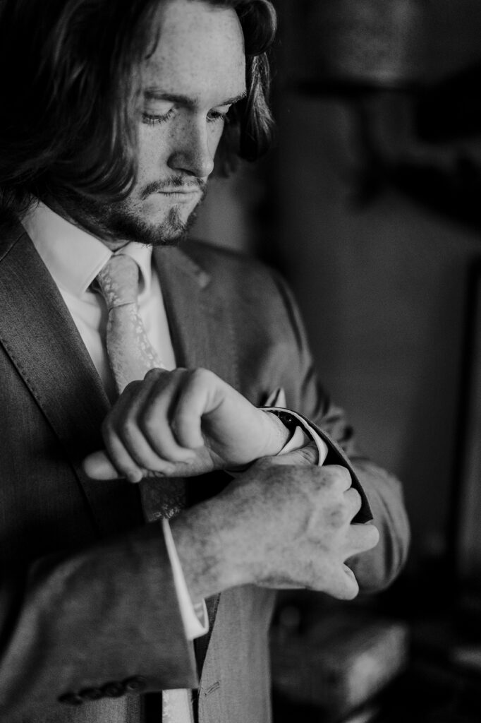 Trace fixes his cufflinks before his Kansas lake house wedding.