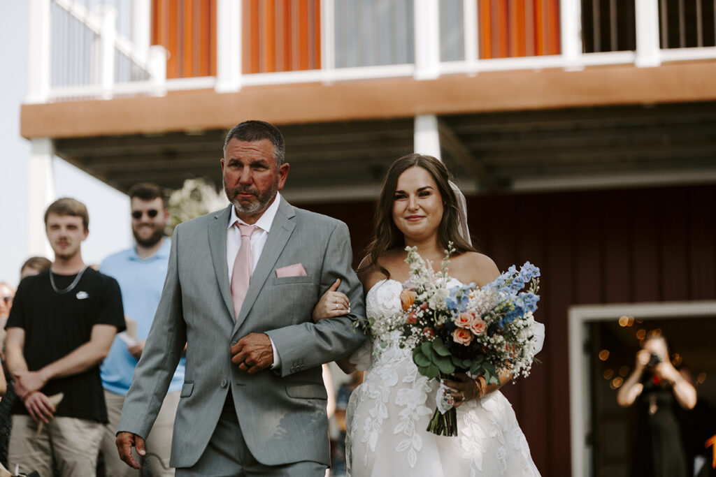 The bride's dad walks her down the aisle during Katie and Trace's Kansas lake house wedding.
