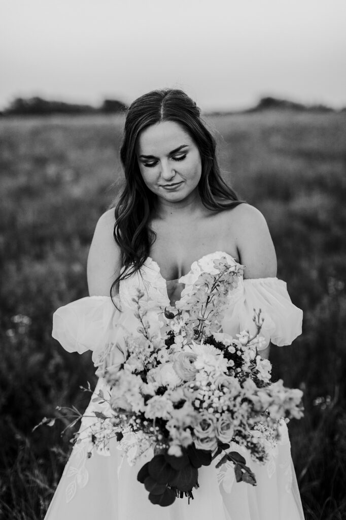 The bride looks down at her bouquet after her Kansas lake house wedding.