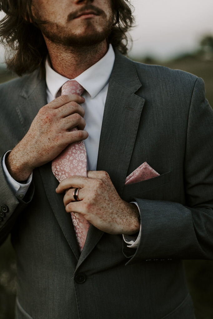 The groom adjusts his tie after his Kansas lake house wedding.