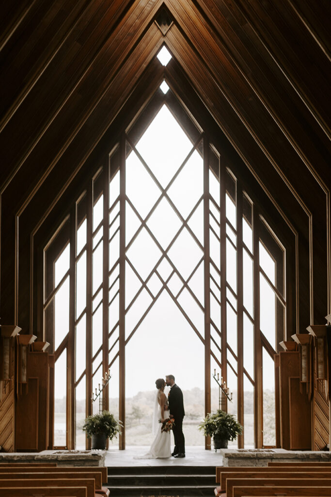 The couple kiss at the front of the Marjorie Powell Allen Chapel.