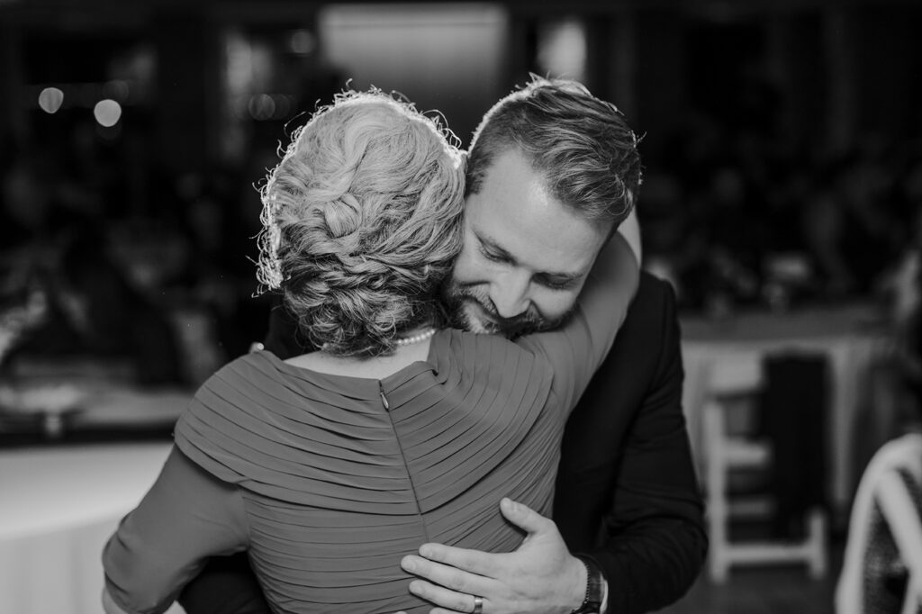 The groom's mom hugs him tightly after their mother/son dance.
