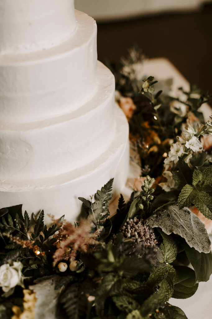 A white cake is surrounded by flowers