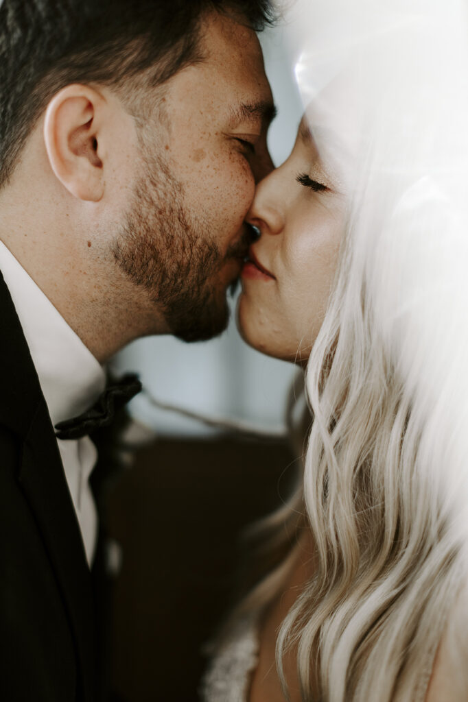 The bride and groom kiss under her veil