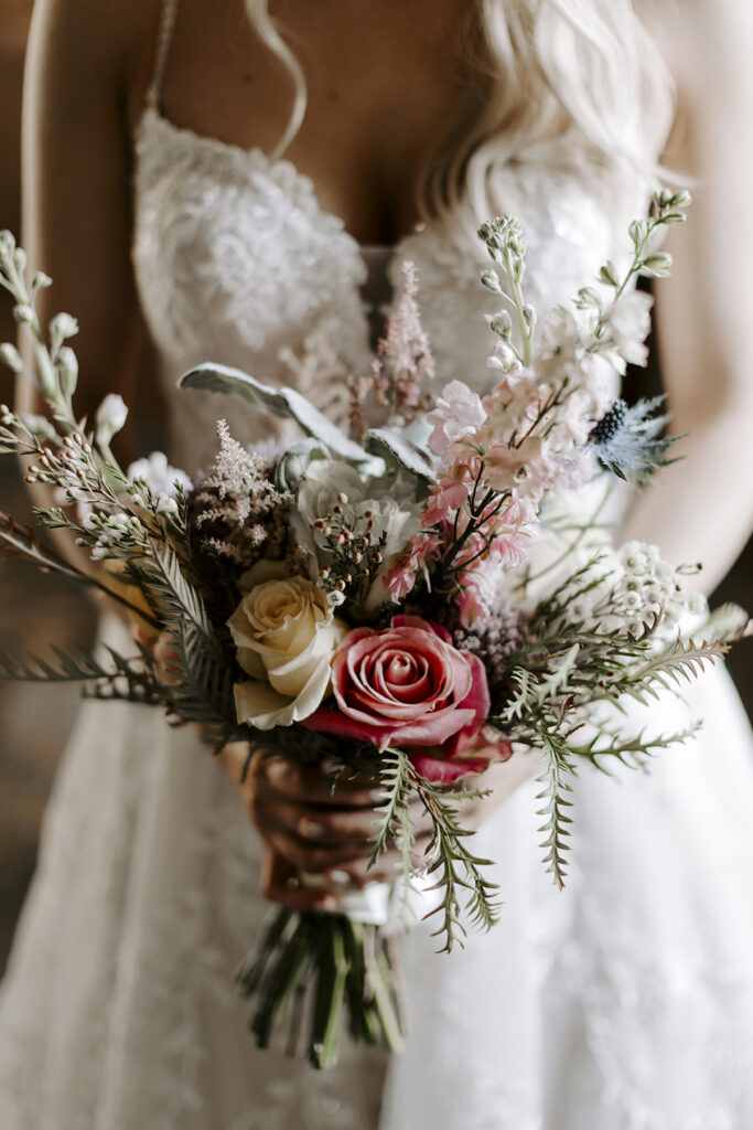 The bride holds a stunning bouquet of roses and snapdragons