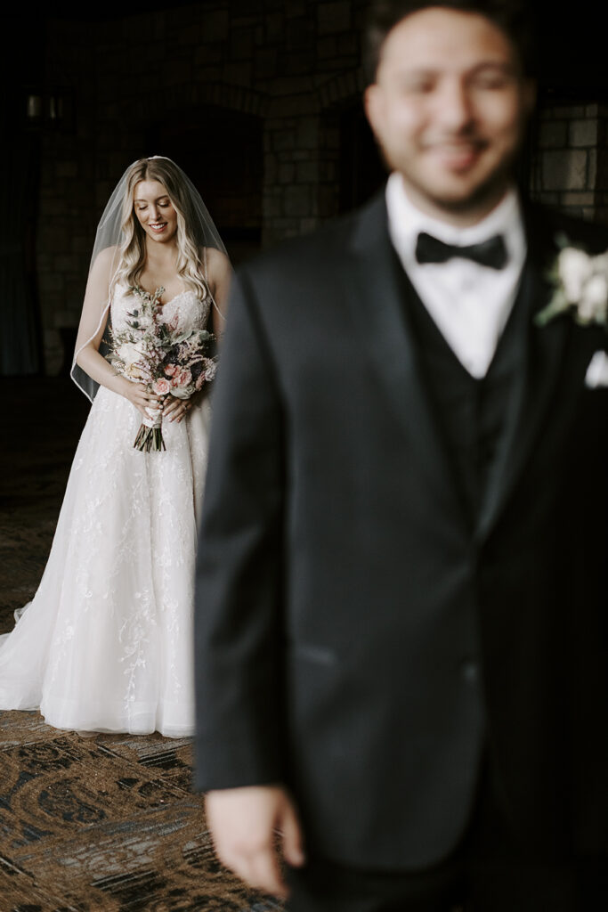 Michelle looks down before Sailor turns to look at her during their first look at their Oread wedding in Lawrence KS