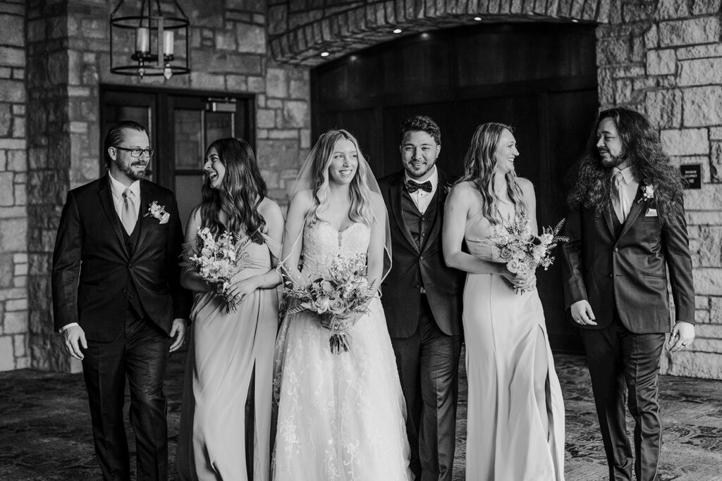 The wedding party chat and walk toward the camera at Michelle and Sailor's Oread wedding in Lawrence KS