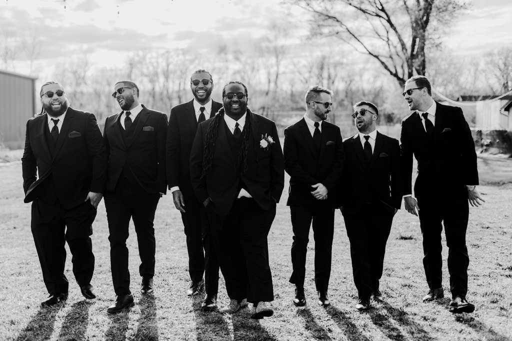 The groom and his groomsmen walk toward the camera and talk after the North Lawrence wedding.